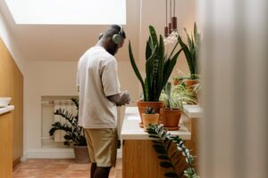 Man in Headphones Standing by Dresser with Plants